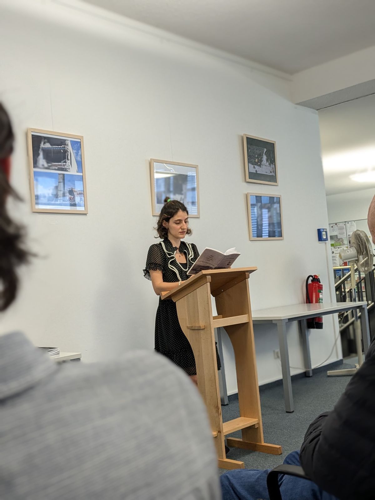 Liza Cemel reading from her book beside photographs of Antakya